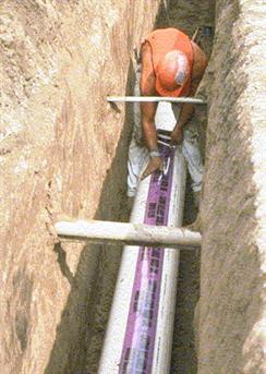 worker with pipes in a ditch